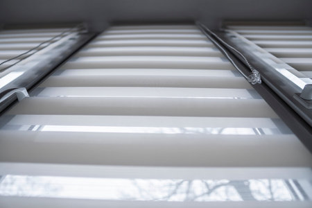 Details of white fabric roller blinds on the white plastic window in the living room. Close up on...