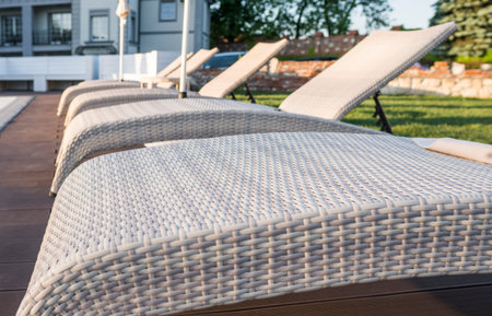 Sunbed near pool with clean water in sunny day.