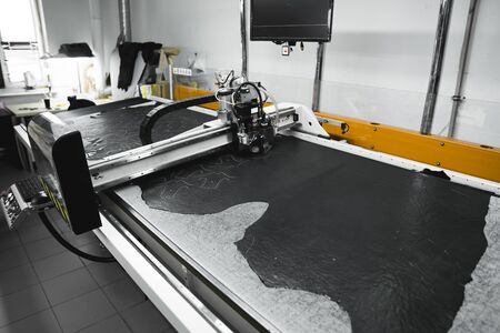 CNC machine for cutting fabrics textile materials and leather. Modern footwear production. Industrial multi-layer leather and fabric cutting machineの写真素材