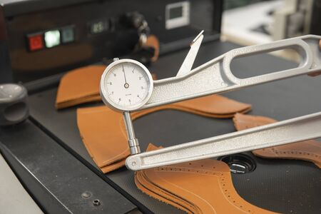 Woman hands use Leather thickness gauge on with a natural brown leather. Preparing of the raw materials for manufacture of bags, shoes, clothing and accessoriesの写真素材