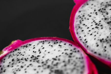 Dragon fruit. Vibrant Dragon Fruit on black background. Sliced white dragon fruit or pitaya on black plate on the table, close-up. Tropical and exotic fruits. Healthy and vitamin food concept.の写真素材