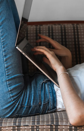 Woman with a laptop laying on a sofa. Study and work online, freelance. Self employed woman, girl...