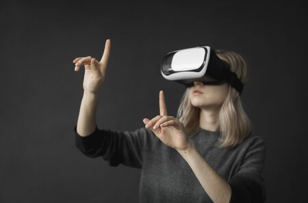 Young woman wearing virtual reality goggles headset, vr box. Connection, technology, new generation, progress concept. Girl trying to touch objects in virtual reality.の写真素材