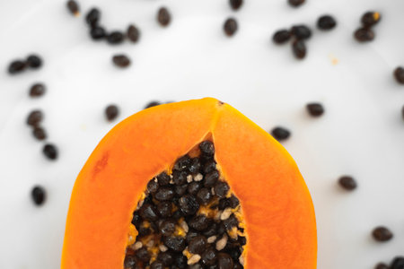 Half cut ripe papaya with seed on a white plate. Slices of sweet papaya with a white background....