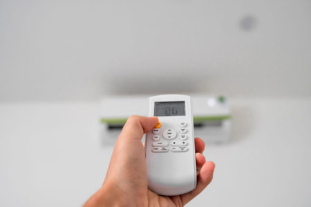 Mans hand using remote controler. Hand holding rc and adjusting temperature of air conditioner...