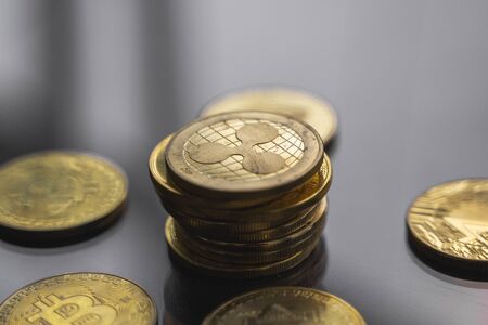 Stack of golden Ripple bitcoin coin with a lot of bitcoins coins on a table. Virtual cryptocurrency concept. Mining of bitcoins online bussiness. Bitcoins trading.の写真素材