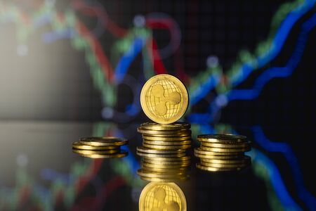 Ripple coin and virtual money concept. Gold Ripple on a stack of coins with chart of growing and falling valuance of a cryptocurrency. Mining or blockchain technology.の写真素材
