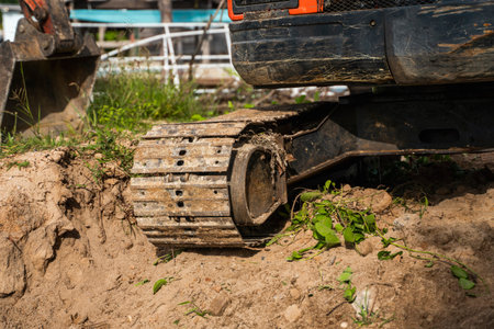 Small orange excavator on a ground against blue sky and sea for a works on construction site. Small...