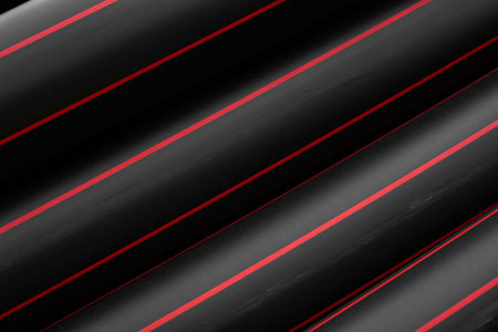 Black rubber or plastic pipes with a red lines as a construction material and equipment at building...