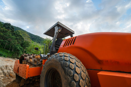 Soil compactor with vibratory padfoot drum. Heavy duty machinery working on highway construction...