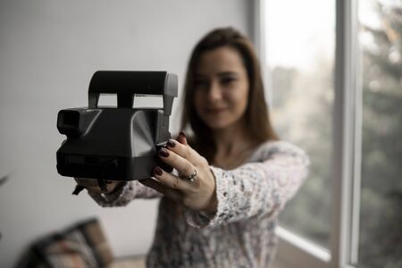 Smiling young brunette woman takes photographs selfie portrait with old photo camera.の写真素材