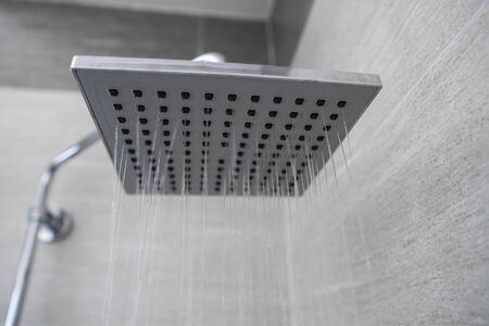 Water flowing from the square shower head in a modern bathroom. Shower in the bathroom with water spray or water. A stream of fresh water from the shower head to clean the dirty bodyの写真素材