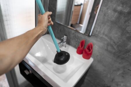 Toilet repair by hand with a Toilet Plunger. Plumbing. A plumber uses a plunger to unclog a toilet. Toilet Plungerの写真素材