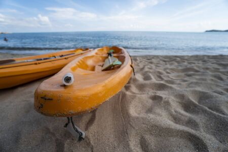 Two colorful orange kayaks on a sandy beach ready for paddlers in sunny day. Several orange recreational boats on the sand. Active tourism and water recreationの写真素材