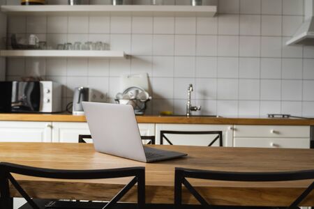 Close Up of laptop on kitchen counter with kitchen on background.の写真素材
