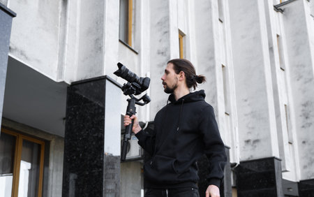 Young Professional videographer holding professional camera on 3-axis gimbal stabilizer. Pro...