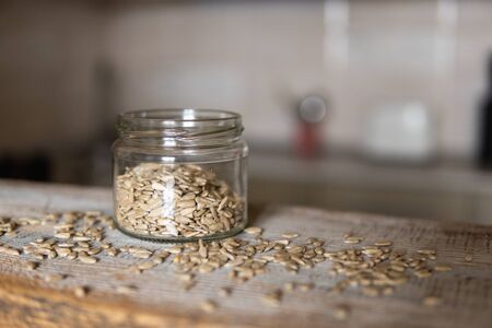 Sunflower seeds in a jar and scattered seed on the white vintage table with a kitchen on background. Healthy vegetarian protein nutritious food. Sunflower seed on rustic old woodの写真素材