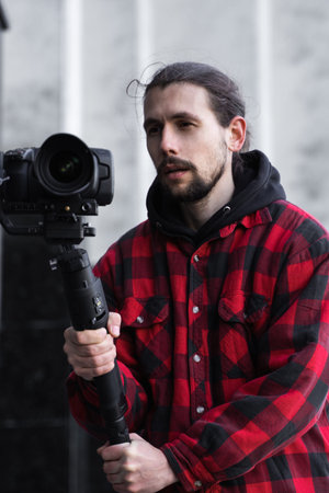 Young Professional videographer holding professional camera on 3-axis gimbal stabilizer. Pro...