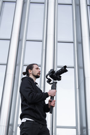 Young Professional videographer holding professional camera on 3-axis gimbal stabilizer. Pro...
