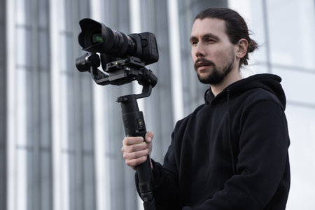 Young Professional videographer holding professional camera on 3-axis gimbal stabilizer. Pro...