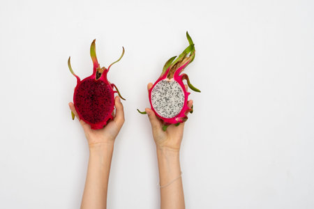 Female hands holding a two half of the ripe dragon fruit on white background.