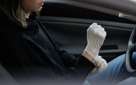Woman in protective medical mask is wearing rubber gloves for protect himself from bacteria virus while planning to drive. Protective mask while quarantine, pandemic, covid 19, coronavirus, infection.の写真素材
