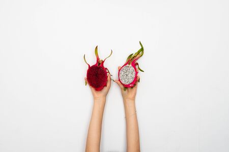 Female hands holding a two half of the ripe dragon fruit on white backgroundの写真素材