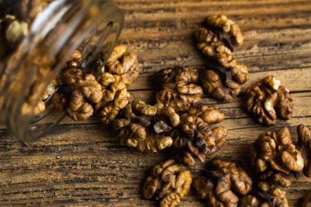 Walnut scattered on the wooden vintage table from a jar. Walnut is a healthy vegetarian protein...