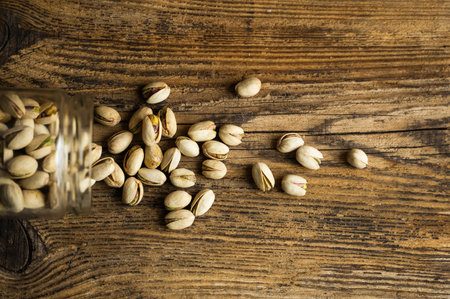 Pistachios scattered on the whooden vintage table from a jar. Pistachio is a healthy vegetarian protein nutritious food. Pistachios on rustic old woodの写真素材