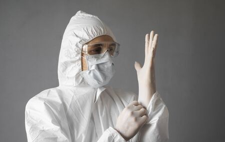 Doctor in white protective suit, medical mask and rubber gloves is ready for helping a people while coronavirus pandemic threat. Epidemic, pandemic of coronavirus covid 19. Doctor in respirator.の写真素材