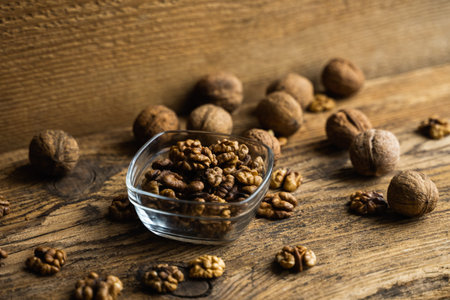 Walnut in a smale plate with scattered shelled nuts and whole nut which standing on a wooden vintage...