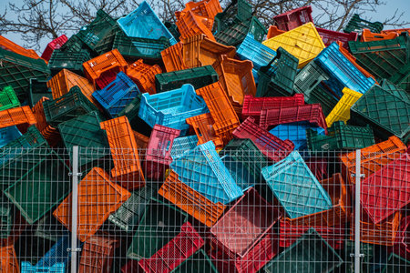 Old plastic boxes in a warehouse as a trash behind the metal mesh fence.
