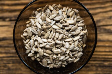 Sunflower seeds in a small plate on the wooden vintage table. Healthy vegetarian protein nutritious food. Sunflower seed on rustic old wood.の写真素材