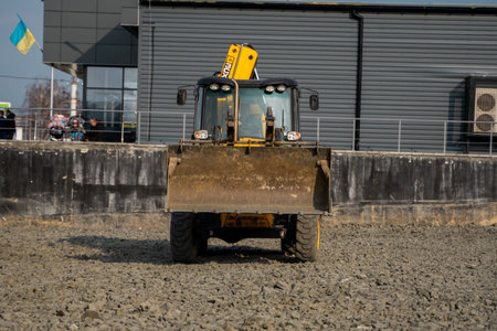 UKRAINE, LUTSK - April 10, 2020: Yellow wheel loader Excavator machine working at construction site...