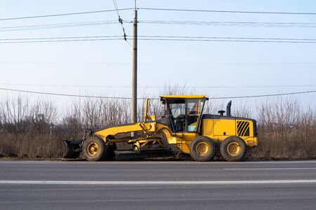 Grader is working on road construction. Grader industrial machine on construction of new roads. Heavy duty machinery working on highway. Construction equipment. Compaction of the roadの写真素材