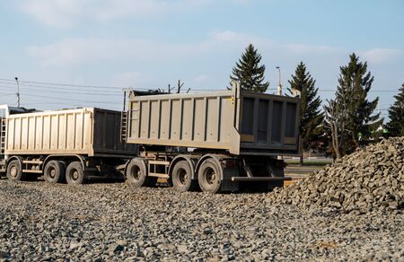 A dump truck is dumping gravel on a construction site. Dump truck dumps its load of gravel on a new road construction project. Road building. Preparing of the fundament for a asphaltingの写真素材