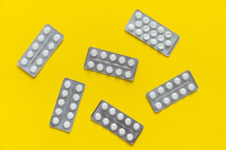 Top view on the pills in the package. White pills on yellow background. Medicine, medication, painkillers, tablet, medicaments, drugs, antibiotic, vitamin, treatment, capsule, dose. Pharmacy theme.の写真素材