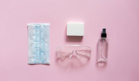 Medical protective mask, respirator ffp, soap, rubber gloves, antiseptic and protective glasses lie on a pink background. Anti-virus protection kit against covid-19. Coronavirus pandemic 2019.の写真素材