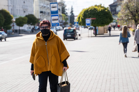 UKRAINE, KYIV - April 25, 2020: Woman wearing a medical mask to prevent of bacterial infection Corona virus or Covid 19 epidemic walking on the street.のeditorial素材