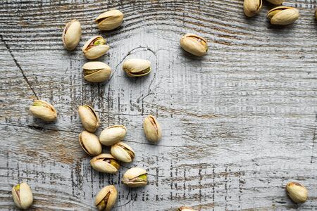 Pistachios scattered on the wooden vintage table. Pistachio is a healthy vegetarian protein nutritious food. Pistachios on rustic old woodの写真素材