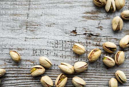Pistachios scattered on the wooden vintage table. Pistachio is a healthy vegetarian protein nutritious food. Pistachios on rustic old woodの写真素材