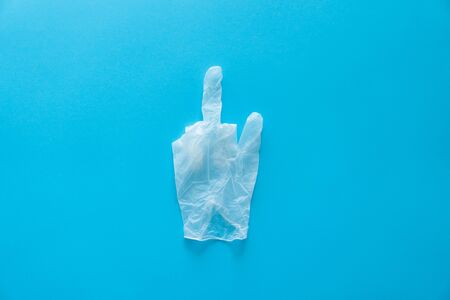 Rubber gloves in a middle finger pose lie on a blue background. Anti-virus protection kit against covid-19. Coronavirus pandemic 2019.の写真素材