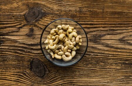 Cashew nuts in a small plate on a vintage wooden table as a background. Cashew nut is a healthy vegetarian protein nutritious foodの写真素材