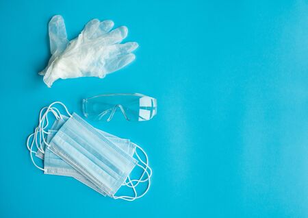 Medical protective mask, rubber gloves and protective glasses lie on a blue background. Anti-virus protection kit against covid-19. Coronavirus pandemic 2019.の写真素材