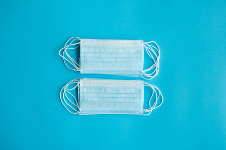 Medical protective masks on a blue background. Disposable 3-ply medical mask to cover the mouth and...