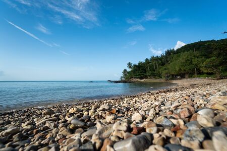 Beach with a small rocks with a palm trees on a horizon.の写真素材