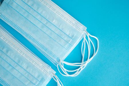 Medical protective masks on a blue background. Disposable 3-ply medical mask to cover the mouth and nose to prevent coronavirus. Coronavirus quarantine. Antivirus medical mask for protection covid-19.の写真素材