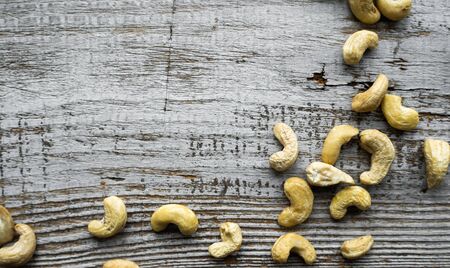 Cashew nuts scattered on the wooden vintage table. Cashew nut is a healthy vegetarian protein nutritious food.の写真素材