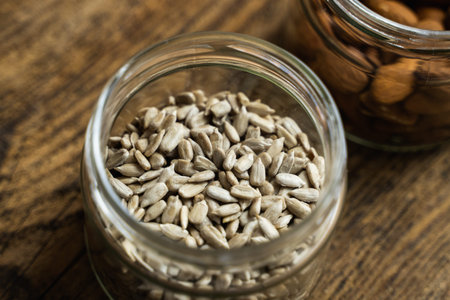 Sunflower seeds in a small jar on the wooden vintage table. Healthy vegetarian protein nutritious food. Sunflower seed on rustic old wood.の写真素材