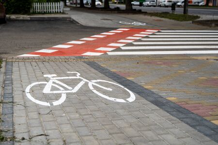 Cycling path with a symbol of bike on a ground through avtomobile road. Bike path in a modern city.の写真素材